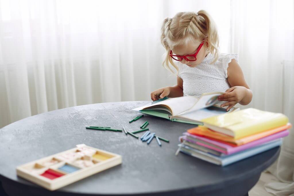 Little girl sitting on a table with books